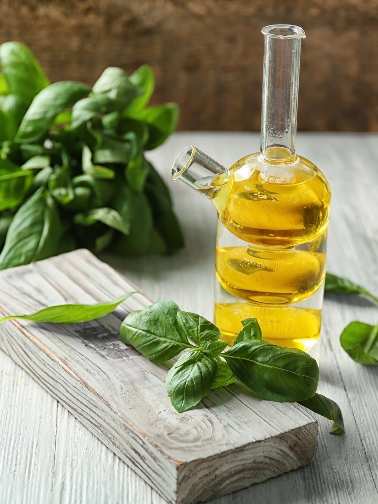 Basilikumöl in eleganter Glasflasche mit frischen Basilikumblättern auf rustikalem Holz – selbstgemachtes Kräuteröl für mediterrane Küche und kreative Rezepte