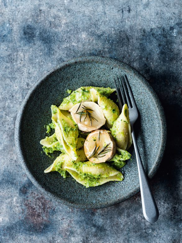 Muschelnudeln mit grünem Spargel-Zitronen-Pesto, serviert mit warmem Ziegenkäse und Rosmarin in einer graublauen Keramikschale auf dunklem Untergrund.