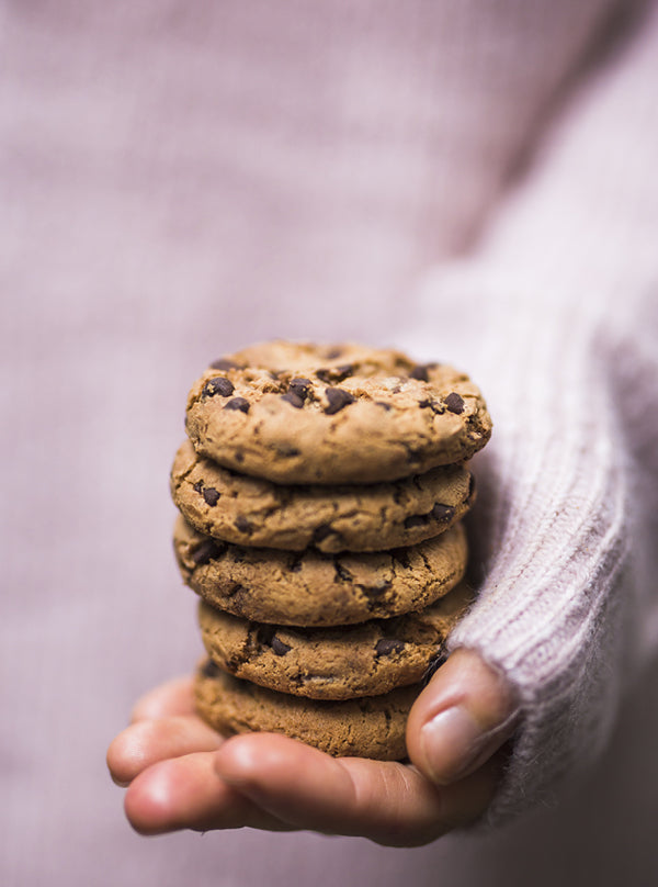 Vegane Chocolate-Chip-Cookies – gestapelte, goldbraune Kekse mit Schokostückchen, in einer Hand gehalten, perfekt weich und frisch gebacken.