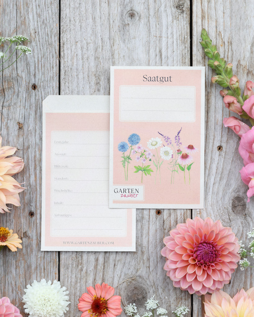A6 Saatguttüten – Gartenzauber Papeterie, Set mit Vorder- und Rückseite auf Holztisch dekoriert mit Blumen.