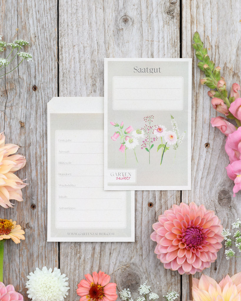 A6 Saatguttüten – Gartenzauber Papeterie, Set mit Vorder- und Rückseite auf Holztisch dekoriert mit Blumen.