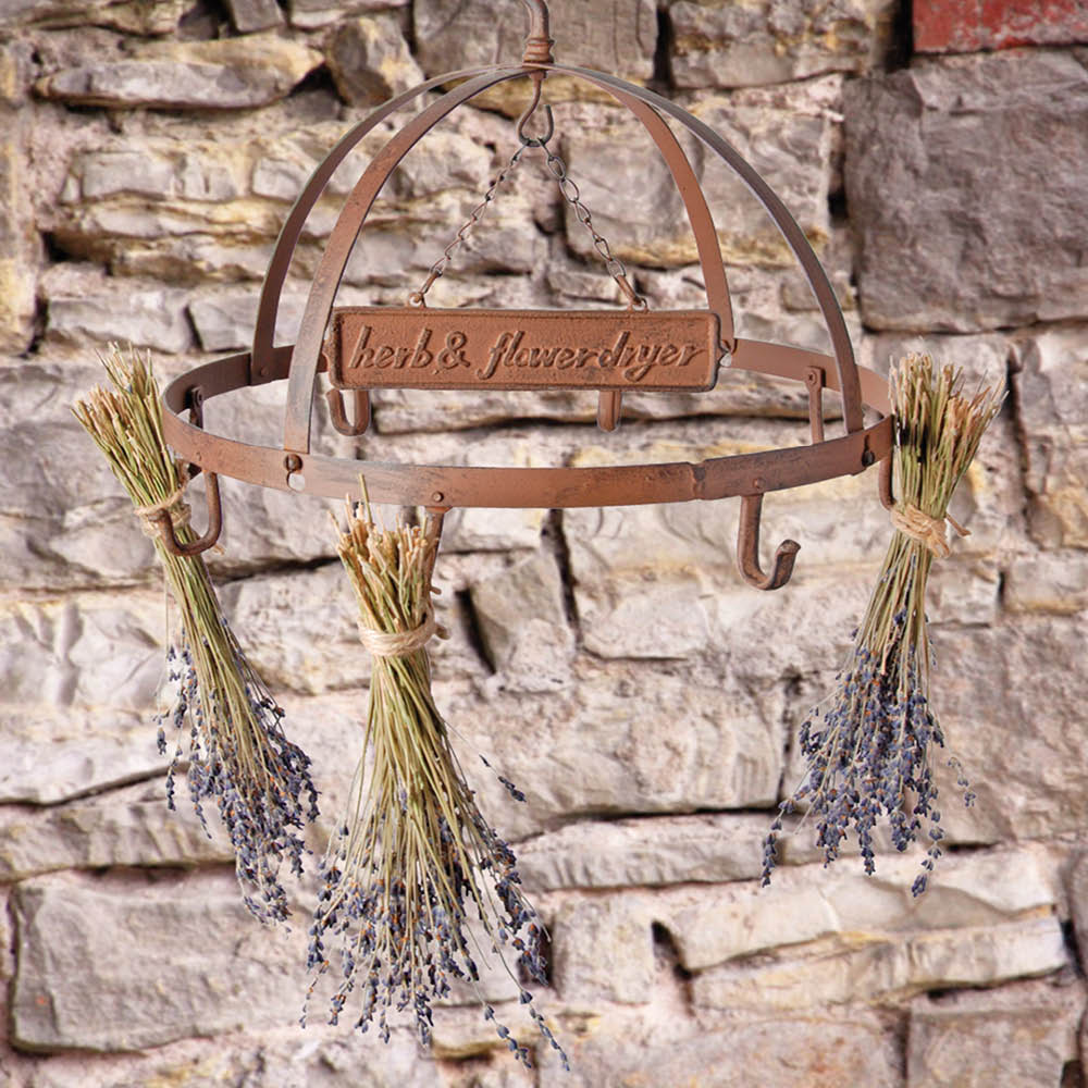 Blumen- und Kräuterhänger aus Gusseisen im Antikfinish mit Lavendelsträußen vor einer rustikalen Steinmauer