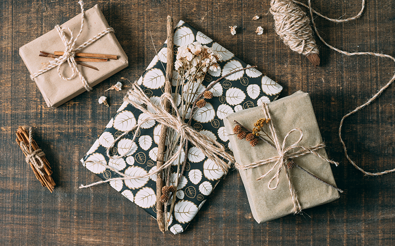 Geschenkset mit schlichter Verpackung und NAturmaterialien als Dekoration auf einem Holztisch.