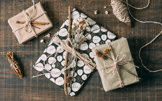 Geschenkset mit schlichter Verpackung und NAturmaterialien als Dekoration auf einem Holztisch.