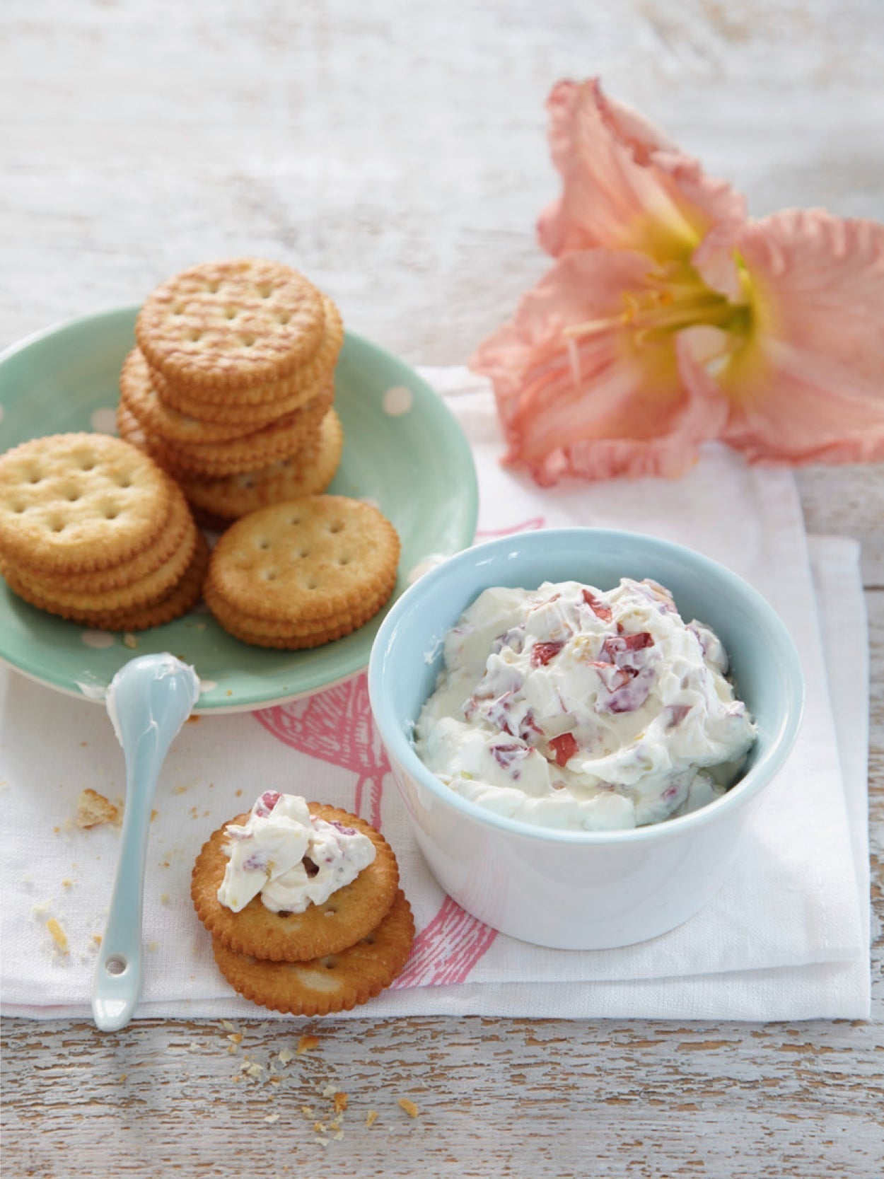 Dekorativer Frischkäse-Dip mit essbaren Taglilienblüten in Schale, serviert mit Baguette