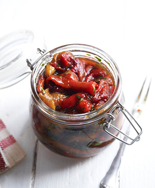 Eingelegte, gegrillte Paprikastreifen in einem Glas mit Bügelverschluss – bunt, aromatisch und mit frischen Kräutern verfeinert