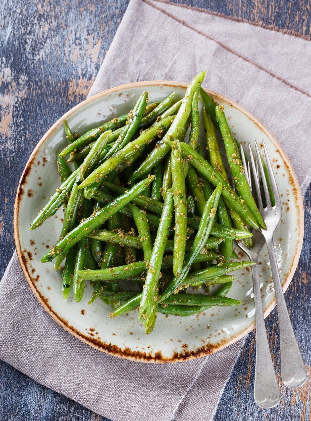 Grüne Bohnen auf einem Teller angerichtet, umhüllt von cremigem Tahina-Dressing mit Gewürzen – veganer Bohnensalat als sommerliches Beilagenrezept