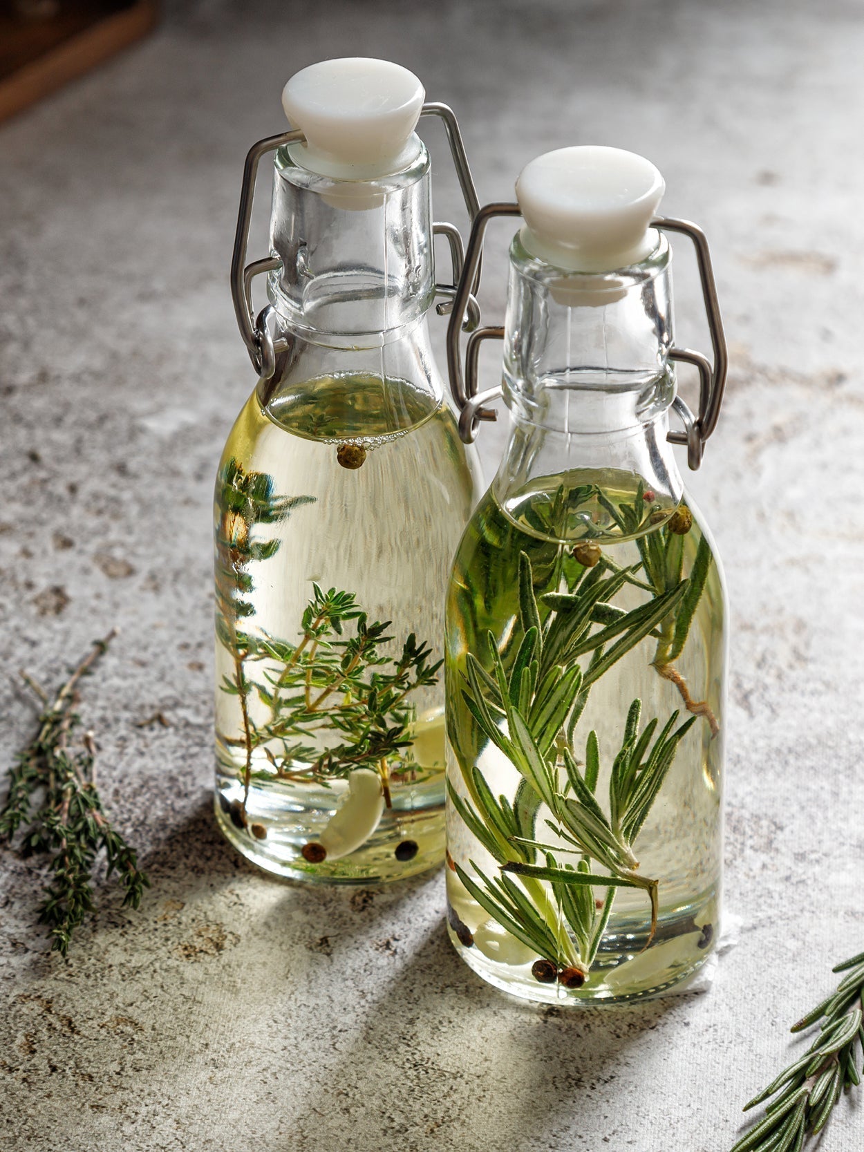 Zwei Flaschen mit Essig, Kräutern und Gewürzen.