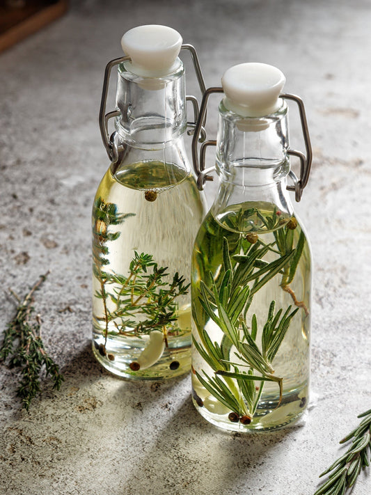 Zwei Flaschen mit Essig, Kräutern und Gewürzen.