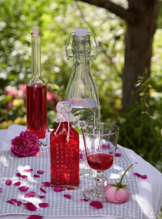 Rosenlikör ein einer dekorativen Flasche auf einem Tisch im Garten.