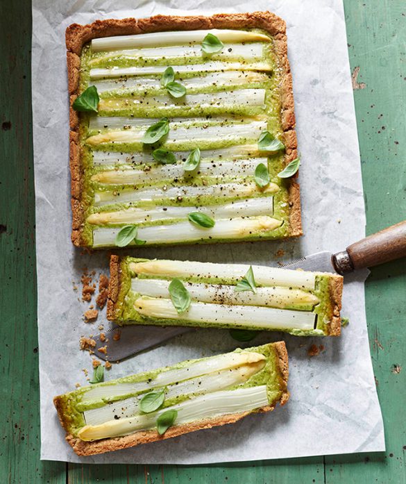 Herzhafte Spargeltarte mit weißem Spargel, Basilikum und goldbraunem Mandelboden – angerichtet auf Backpapier mit Messer.