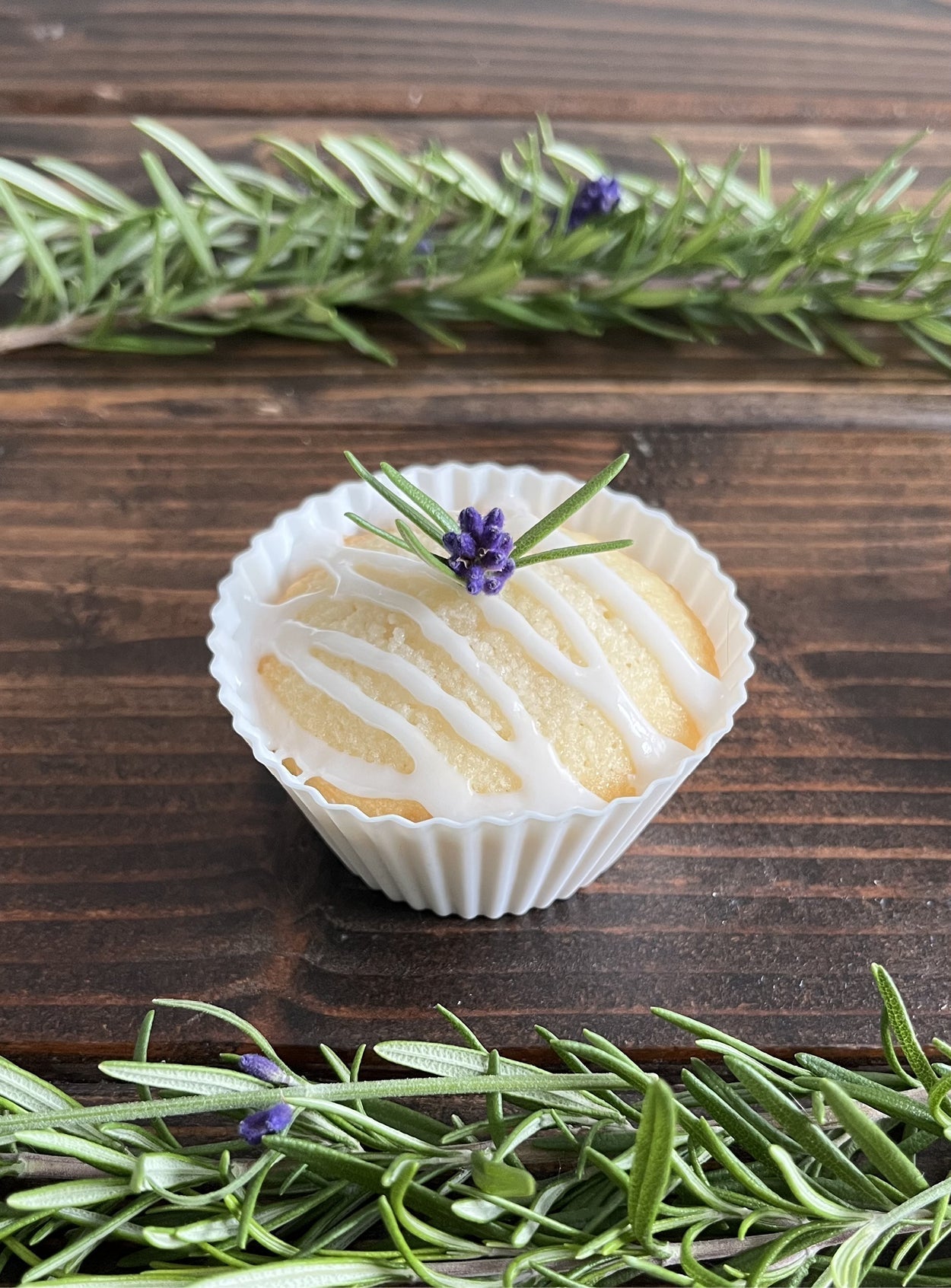Zitronen-Ricotta-Cupcake mit Zuckerguss, dekoriert mit Rosmarin und Lavendelblüte