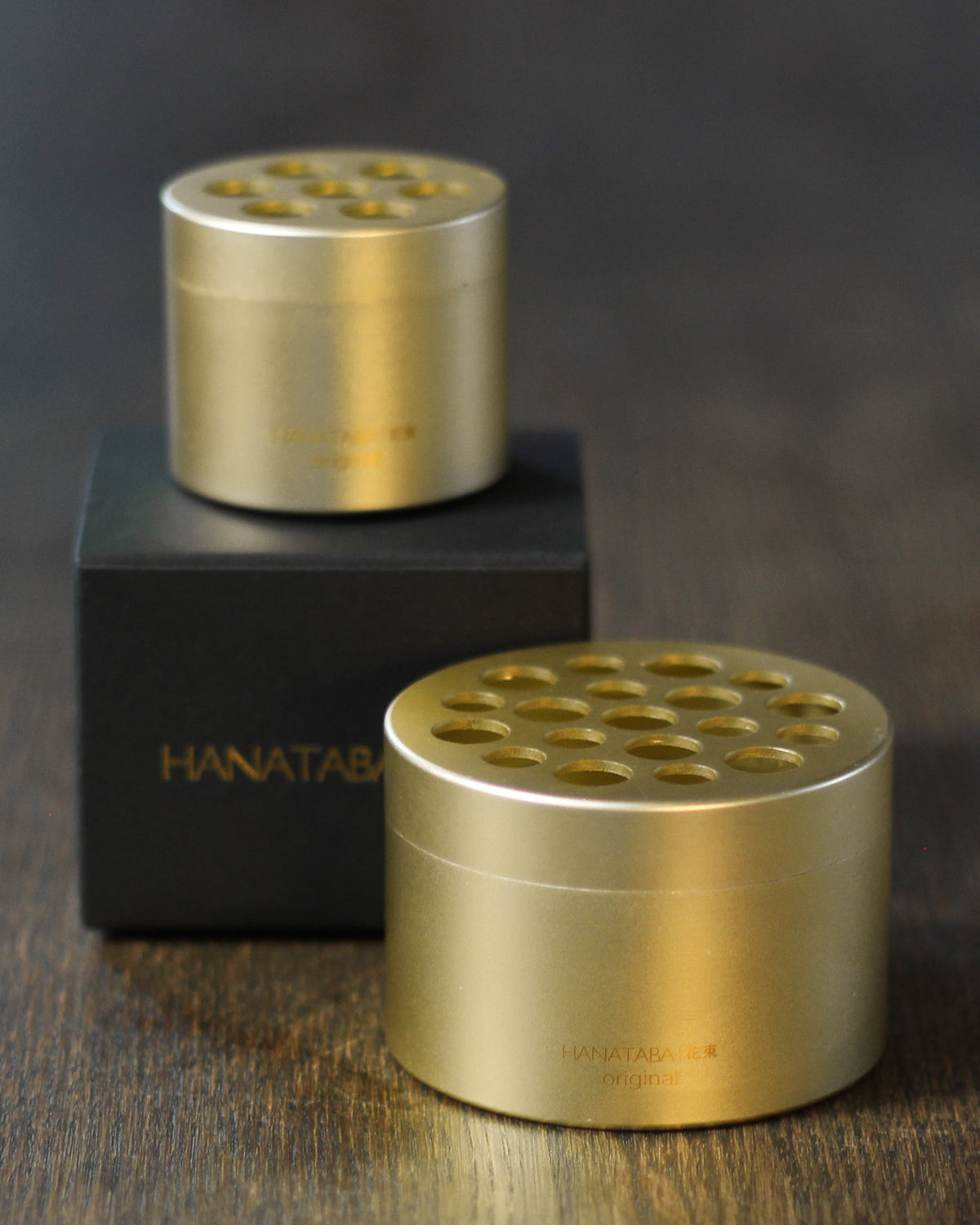 Hanataba in Champagne Gold,  mit edler schwarzer Verpackung auf Holztisch.