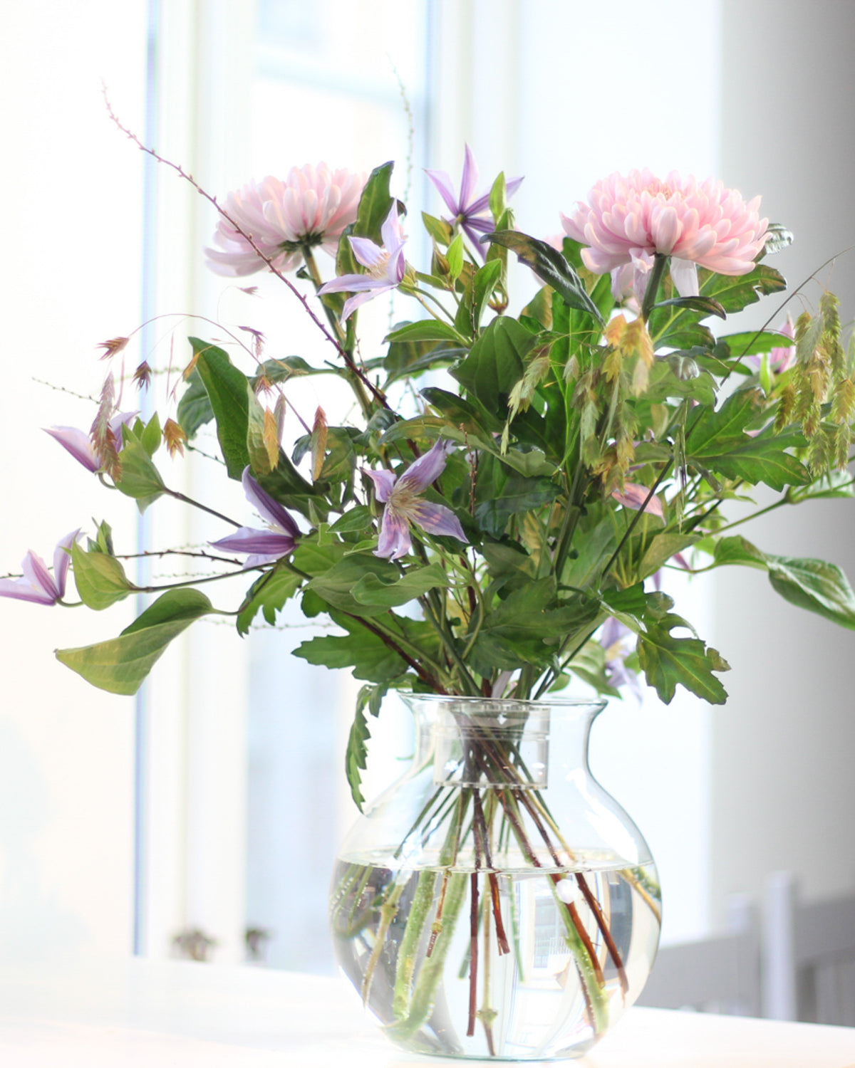 Frischer Blumenstrauß mit Chrysanthemen und Clematis, gebunden mit dem Hanataba „Crystal Clear“.