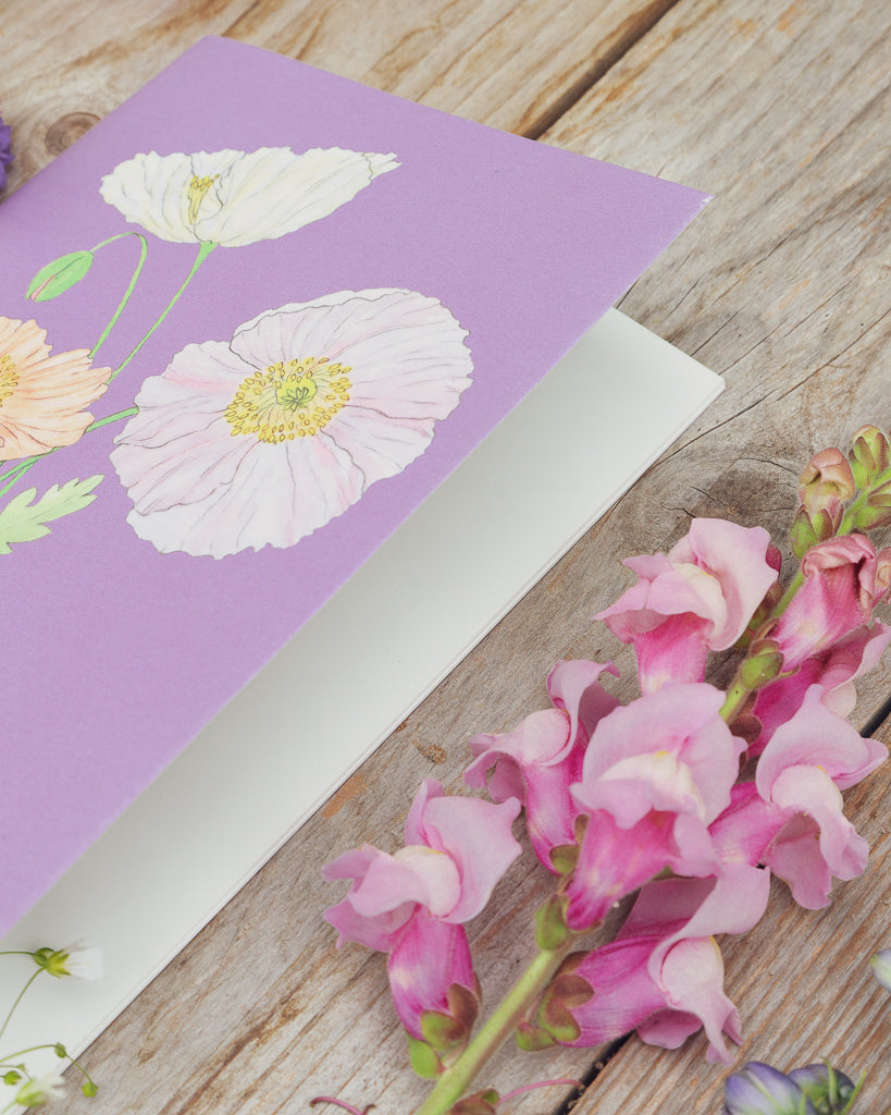 Detailaufnahme des A5 Notizhefts Islandmohn Colibri® Rosa Chiaro – Gartenzauber Papeterie, liegend auf Holztisch mit Blumen.