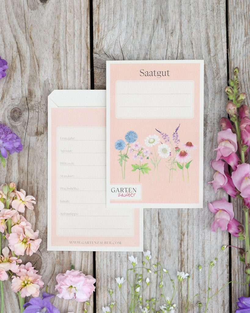 A6 Saatguttüten – Gartenzauber Papeterie, Set mit Vorder- und Rückseite auf Holztisch dekoriert mit Blumen.