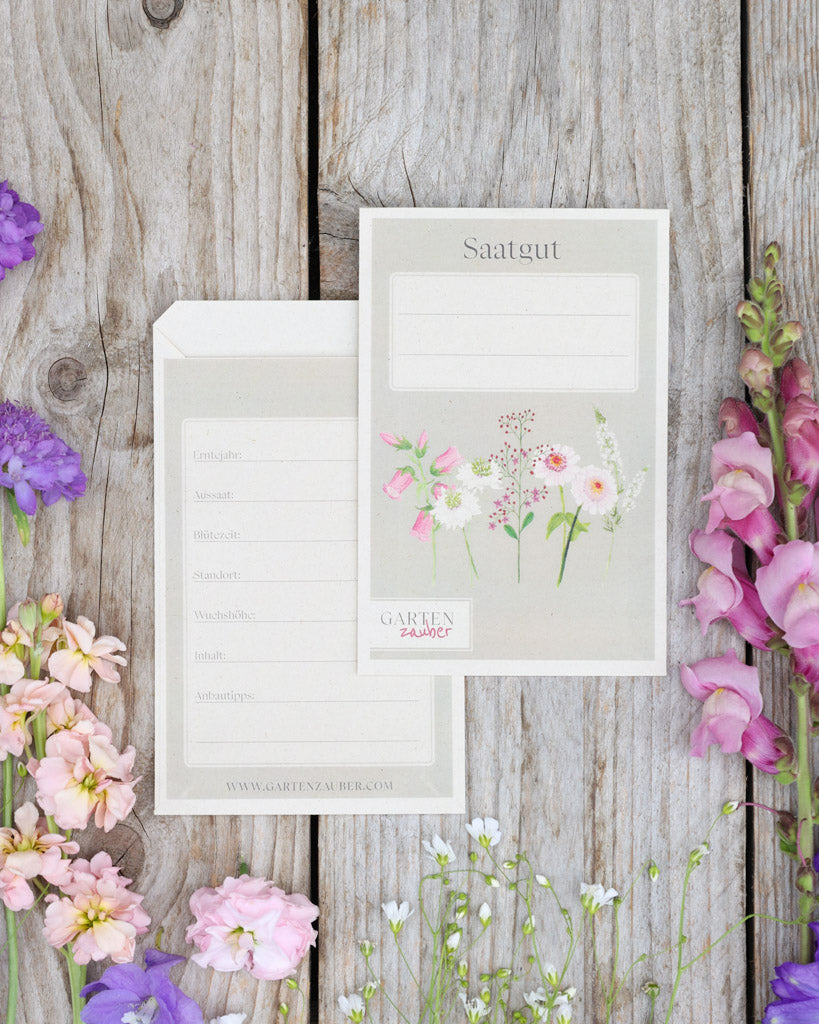 A6 Saatguttüten – Gartenzauber Papeterie, Set mit Vorder- und Rückseite auf Holztisch dekoriert mit Blumen.