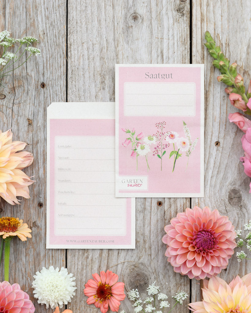 A6 Saatguttüten – Gartenzauber Papeterie, Set mit Vorder- und Rückseite auf Holztisch dekoriert mit Blumen.