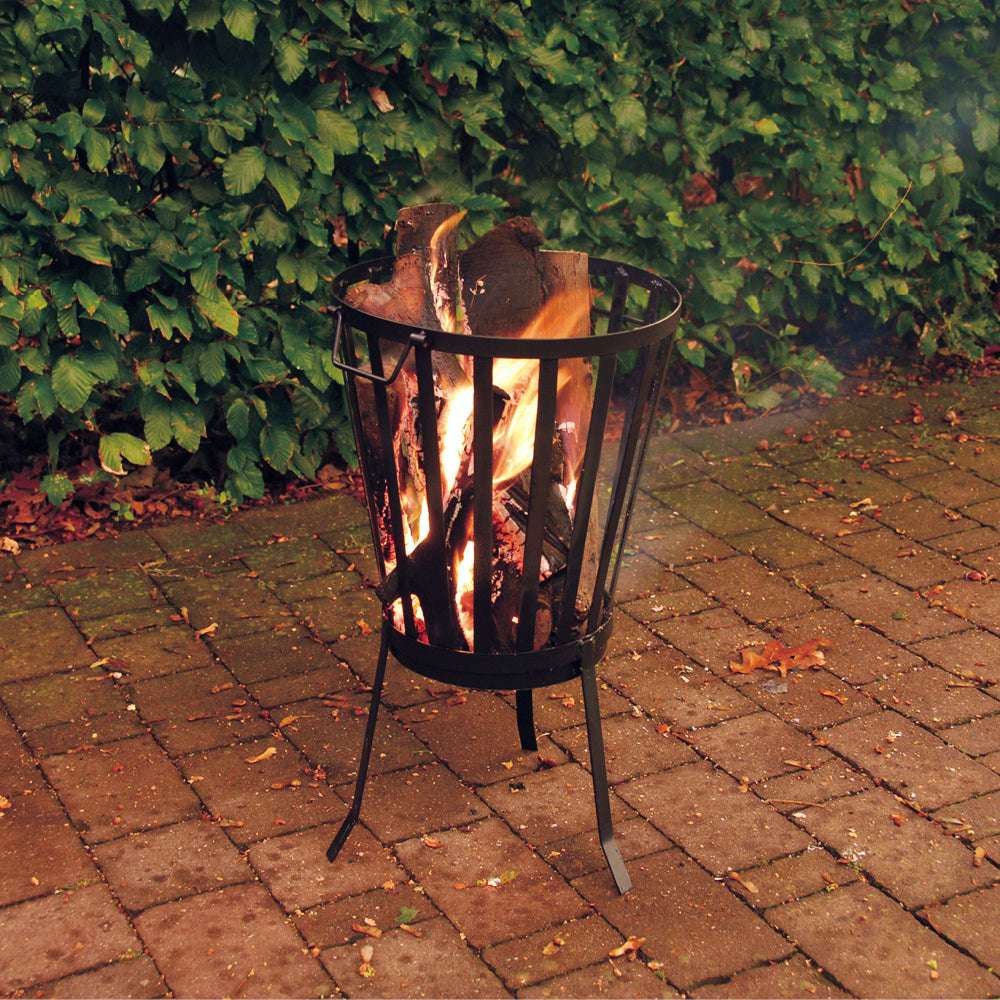 Feuerkorb aus Metall mit Holz im Garten bei Dämmerung