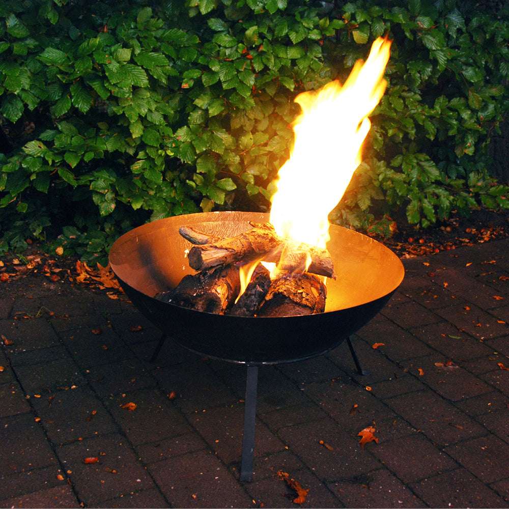 Gusseiserne Feuerschale mit Ständer und brennendem Kaminholz im Garten