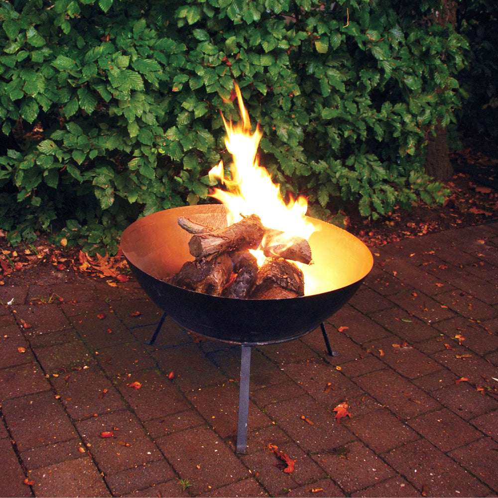 Brennende Feuerschale mit Flammen im Garten bei Abendlicht