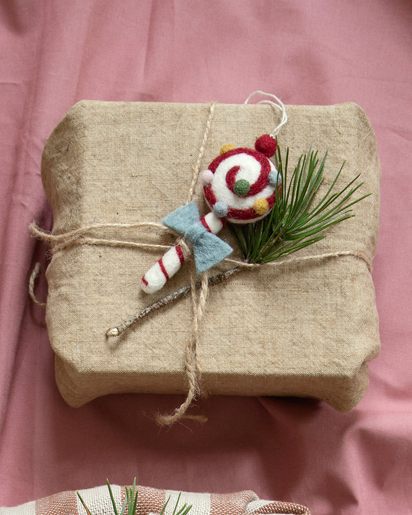 Handgefilzter Weihnachtslolly mit blauer Schleife von Gry & Sif – hier als liebevoller Geschenkanhänger dekoriert.