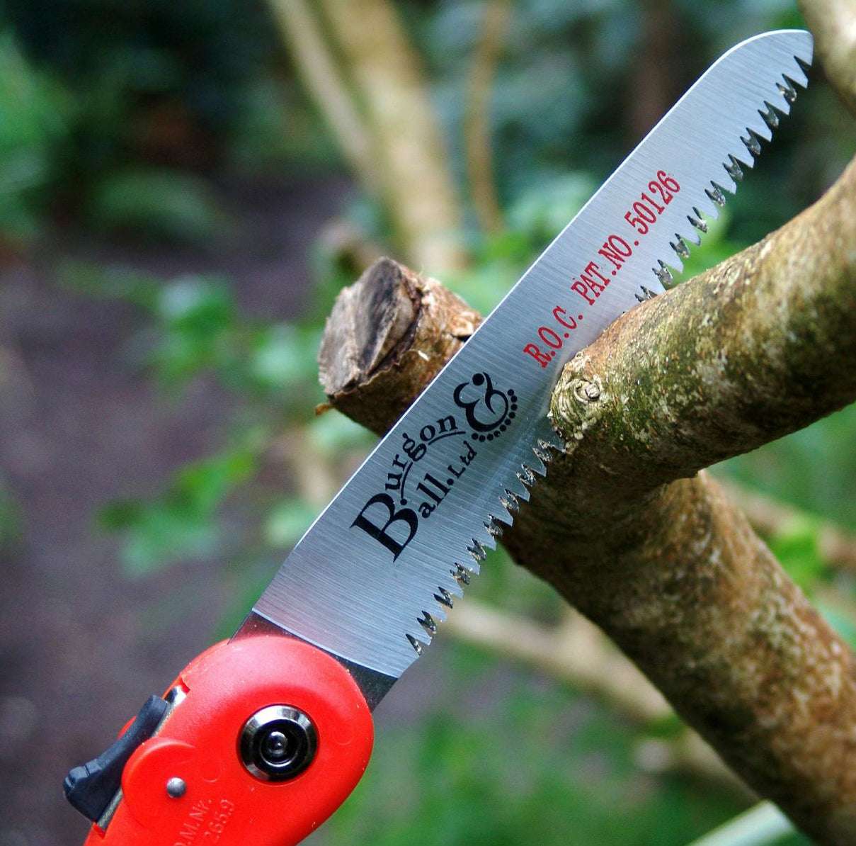 Klappbare Handsäge mit gummiertem Griff schneidet Ast im Garten